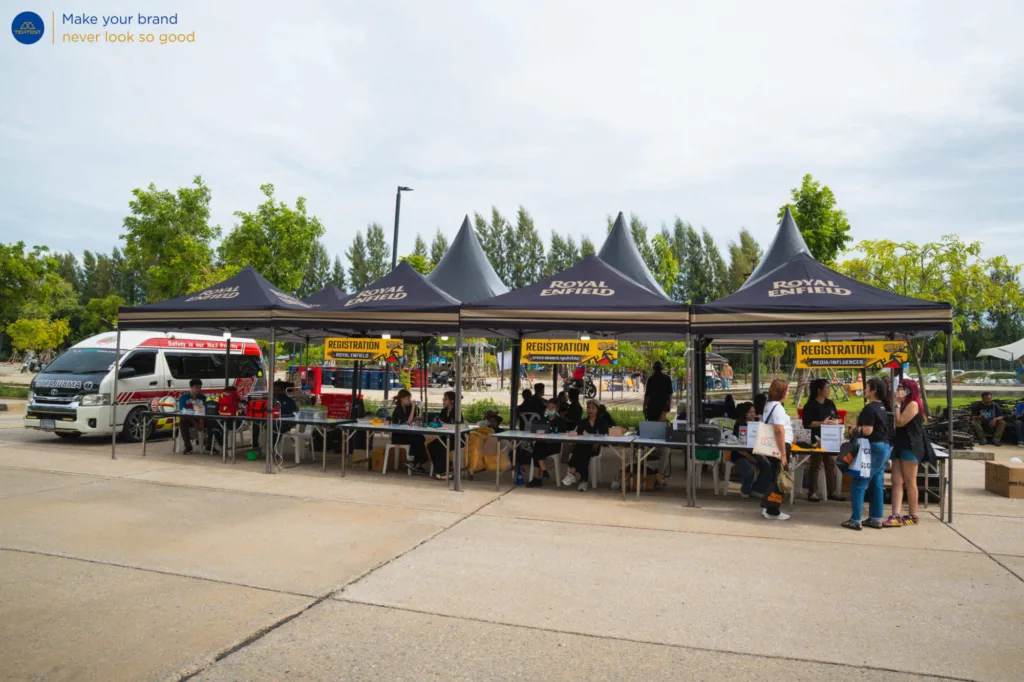 เต็นท์พับ Royal Enfield และธงปีกนกหลายแบบรอบรถที่จัดแสดง