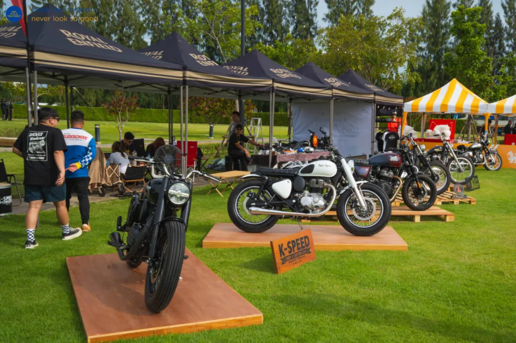 เต็นท์พับ Royal Enfield และธงปีกนกหลายแบบรอบรถที่จัดแสดง