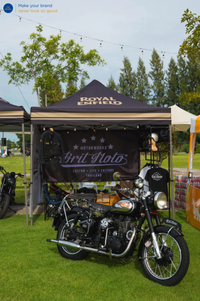 เต็นท์พับ Royal Enfield และธงปีกนกหลายแบบรอบรถที่จัดแสดง