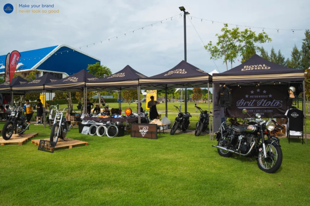 เต็นท์พับ Royal Enfield และธงปีกนกหลายแบบรอบรถที่จัดแสดง