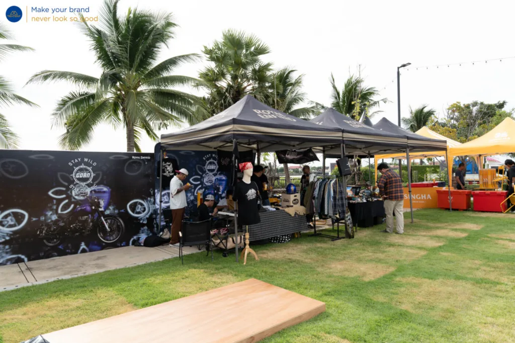 เต็นท์พับ Royal Enfield และธงปีกนกหลายแบบรอบรถที่จัดแสดง