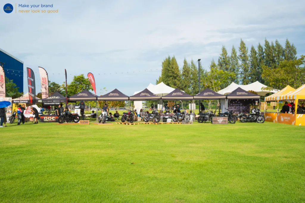 เต็นท์พับ Royal Enfield และธงปีกนกหลายแบบรอบรถที่จัดแสดง