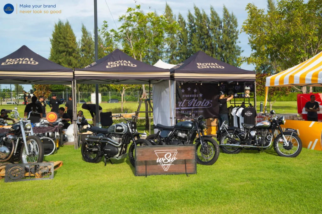 เต็นท์พับ Royal Enfield และธงปีกนกหลายแบบรอบรถที่จัดแสดง