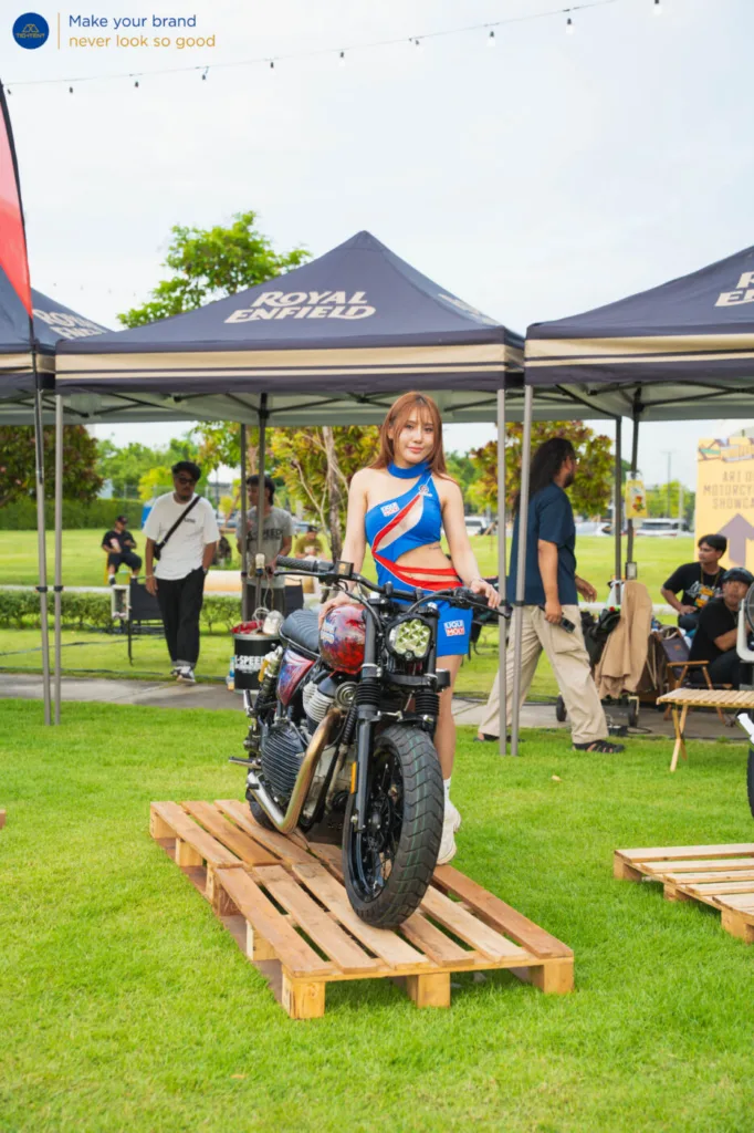 เต็นท์พับ Royal Enfield และธงปีกนกหลายแบบรอบรถที่จัดแสดง