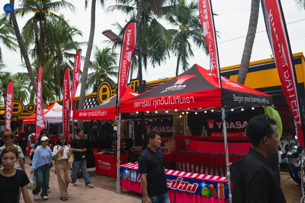 เต็นท์พับ Yuasa สีแดง-ดำ พร้อมธงปีกนกเรียงแถว ผู้ชมเดินผ่านบูธ