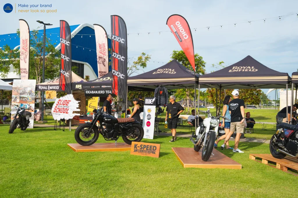 เต็นท์พับ Royal Enfield และธงปีกนกหลายแบบรอบรถที่จัดแสดง
