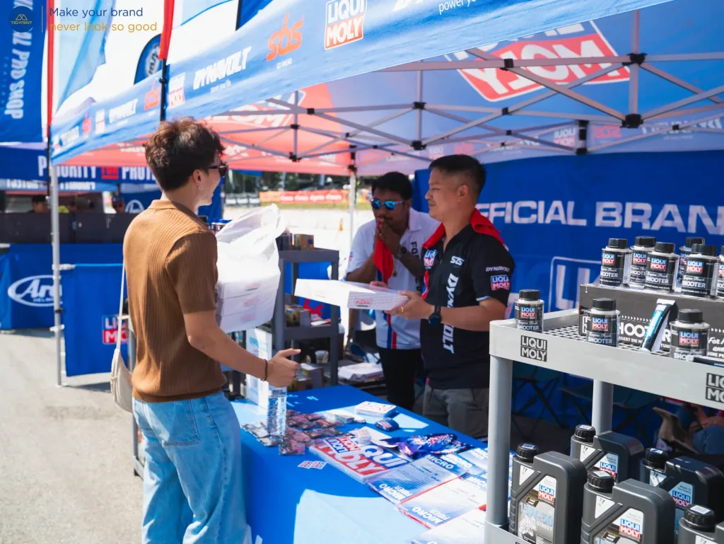 เต็นท์พับและผ้าคลุมโต๊ะพิมพ์โลโก้ Liqui Moly ทีมงานกำลังให้บริการลูกค้า